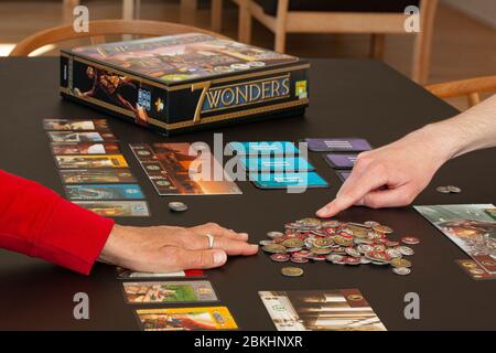 Close-up of hands from people plying the board game 7 Wonders. Stock Photo