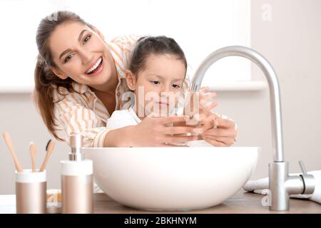Little daughter with her mother washing hands in bathroom Stock Photo