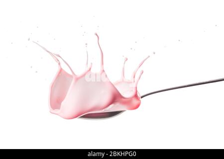 Strawberry splashing into a spoon full of yogurt. Close-up view On white background. Stock Photo