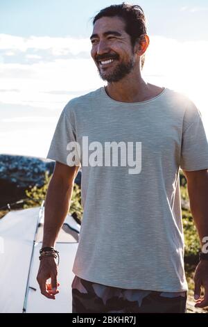 Smily man lit by the sun in a camp site Stock Photo