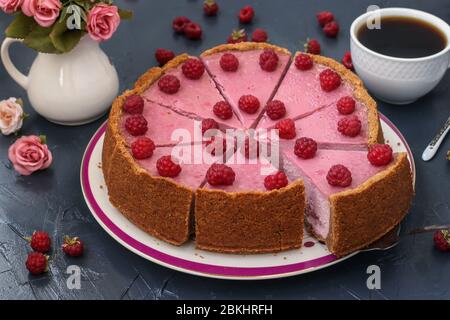 Homemade raspberry cheesecake cut in portions on a plate, located on dark background, Horizontal format Stock Photo