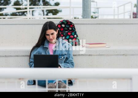 Young university student writes notes in her laptop on campus Stock Photo
