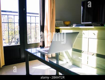 laptop on top of glass table near a window; living room Stock Photo