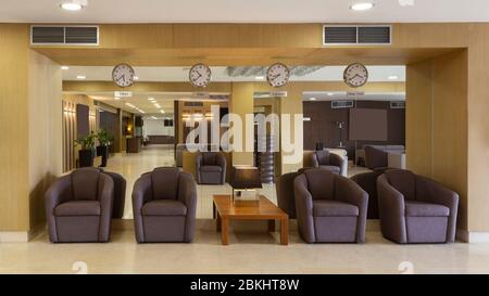 Hotel lobby with brown armchairs and clocks Stock Photo