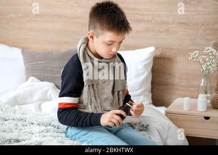Ill little boy with cough syrup in bottle at home Stock Photo