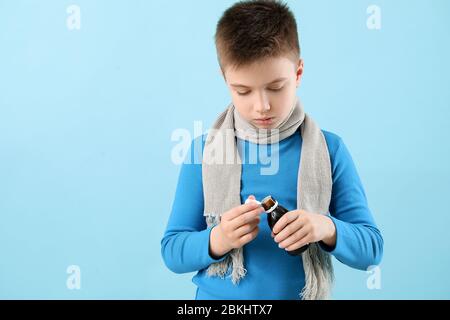 Ill little boy with cough syrup in bottle on color background Stock Photo