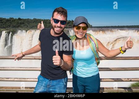 couple posing at the Devil's Throat waterfall at Iguazu Falls Stock Photo