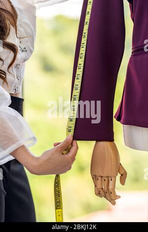 Close-up young adult asian fashion designer using measuring tape to measure suit arm at her atelier studio as sole owner. Using for entrepreneur small Stock Photo