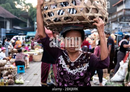 Market vendor carrying a basket above her head in Ubud Morning Market known as Ubud Morning Bazaar Stock Photo