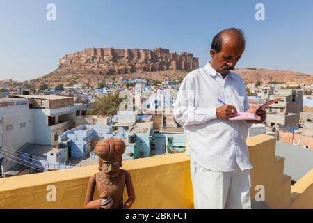 India, Rajasthan, Jodhpur, waiter on Haveli Guest House rooftop restaurant and Fort Mehrangarh in the background Stock Photo