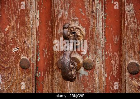 Old wooden door painted with reddish colors with old doorbell. Stock Photo