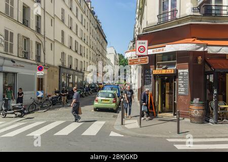 Paris, France - June 23, 2016: Quiet and cozy street of Paris near Montmartre. Nearly parked cars and motorbikes along narrow paving stones and locals Stock Photo