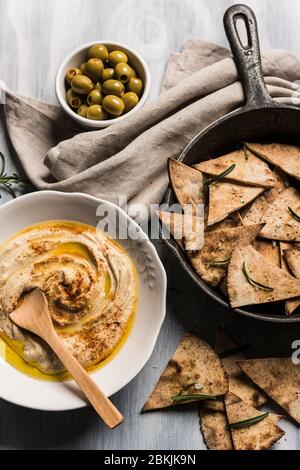 Home made humus bowl, decorated with d olive oil over a rustic wooden clear background. Top View Stock Photo