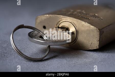 Close-up of a brass padlock with key insterted in to the lock. Stock Photo