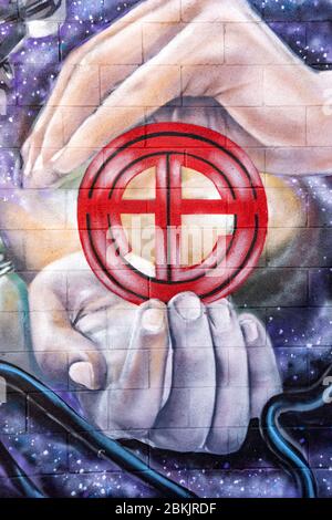 Graffiti art of two large hands holding a small red circular symbol similar to the astrological gical earth sign Stock Photo