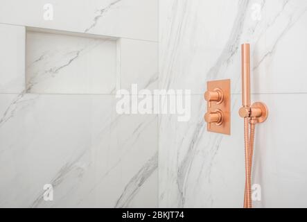 Close Up Of Luxurious White And Gray Marble Tile Shower With Copper Fixtures. Stock Photo