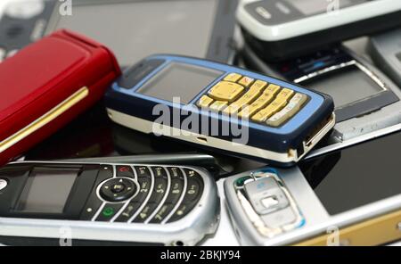 pile of used old mobile damaged phones technology background Stock Photo