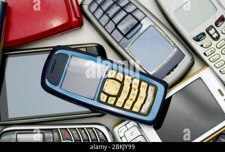 pile of used old mobile damaged phones technology background Stock Photo