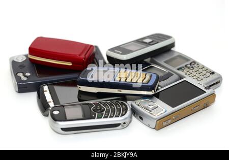 pile of used old mobile damaged phones technology background Stock Photo