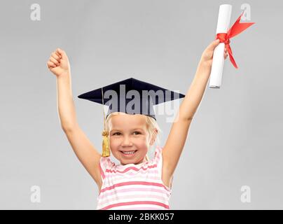 happy little girl in mortarboard with diploma Stock Photo