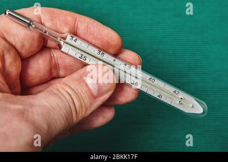 A glass mercury thermometer shows the high temperature of a persons body on its scale. Stock Photo