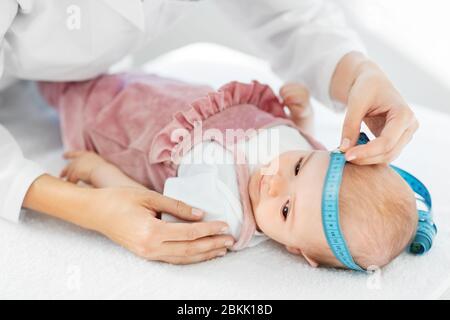 pediatrician doctor measuring bab's head at clinic