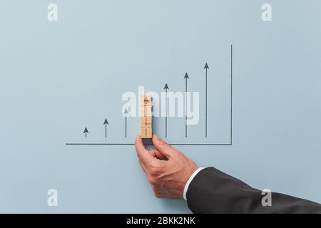 Business economy growth prediction graph - businessman making a chart with upwards pointing arrows. Over blue background. Stock Photo