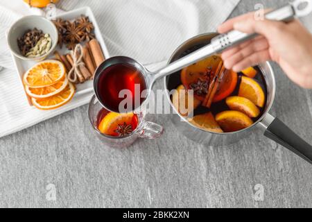 hand with ladle pouring hot mulled wine to glass Stock Photo