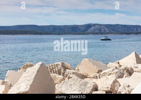 Beautiful big white limestone textured blocks at Bol, Brac, Dalmatia, Croatia and the Adriatic  sea and a boat in the background. Famous stones used f Stock Photo