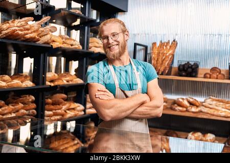 Small Business.Bearded man assistant standing at bakery shop crossed arms smiling cheerful Stock Photo