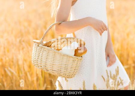 girl with bread and milk in basket on cereal field Stock Photo