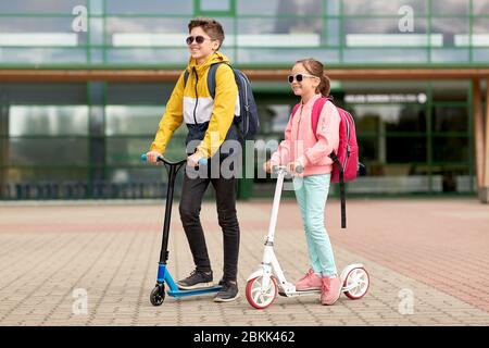 happy school children with backpacks and scooters Stock Photo