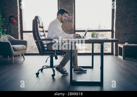 Profile side view of his he nice attractive chic confident focused man qualified IT expert economist sitting in chair preparing report at modern loft Stock Photo