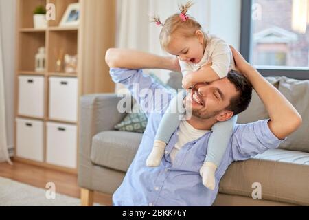 father riding little baby daughter on neck at home Stock Photo