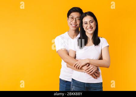 Image of cheerful multinational man and woman hugging and laughing isolated over yellow background Stock Photo
