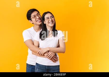 Image of cheerful multinational man and woman hugging and looking upward isolated over yellow background Stock Photo