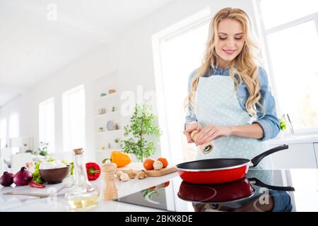 Photo of beautiful cheerful housewife watch frying pan checking meal condition add basil spices cooking tasty dinner lunch breakfast modern interior Stock Photo