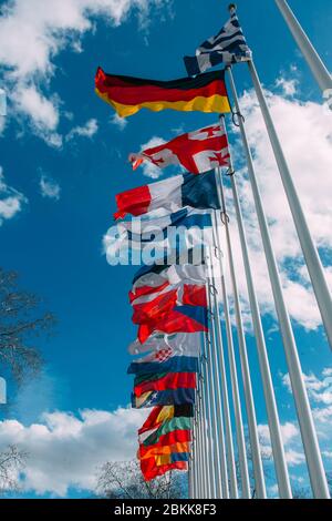 flags of the countries of the world on flagpoles against the blue sky ...