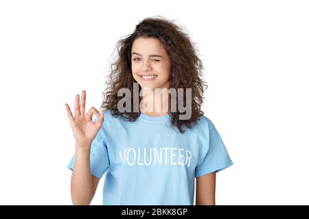 Smiling hispanic teen girl volunteer shows ok sign isolated on white background. Stock Photo