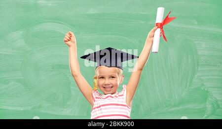 happy little girl in mortarboard with diploma Stock Photo