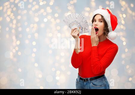 surprised woman in santa hat with money Stock Photo