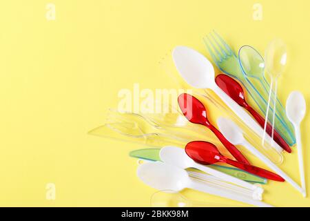 Plastic cutlery, forks, spoons and knives on yellow background. Pollution of the environment with plastic and microplastics. Copy space Stock Photo
