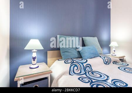 Home modern bedroom in blue marine tones. Lamps shine and headboards. Stock Photo