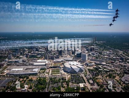 The U.S. Air Force Air Demonstration Squadron, the Thunderbirds, and the Navy Blue Angels, top, fly in formation over Mercedes Benz Stadium, home of the Atlanta Falcons football team, during the America Strong flyover May 2, 2020 in Atlanta, Georgia. America Strong is a salute from the Navy and Air Force to recognize healthcare workers, first responders, and other essential personnel in a show of national solidarity during the COVID-19 pandemic. Stock Photo