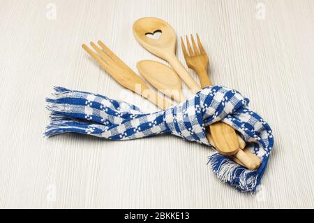 Set of kitchen utensils tied with towel on the light wooden background Stock Photo