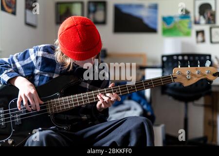 Teenager playing guitar in bedroom as part of homeschool curriculum Stock Photo