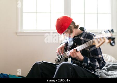 High school student working at home on learning guitar for homework Stock Photo