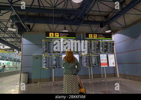 Woman looking at the Departures and arrivals electronic board at the airport, Madrid, Spain Stock Photo