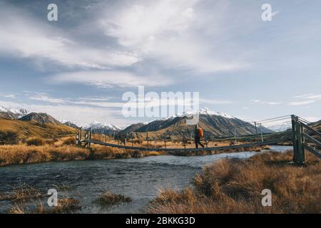 A young man hikes towards the summit of Mt Sunday, Southern Alps, Canterbury, New Zealand. Stock Photo