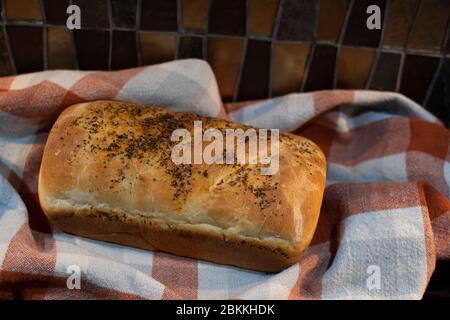 Fresh baked bread on a orange and grey checkered towel sitting on a kitchen counter Stock Photo